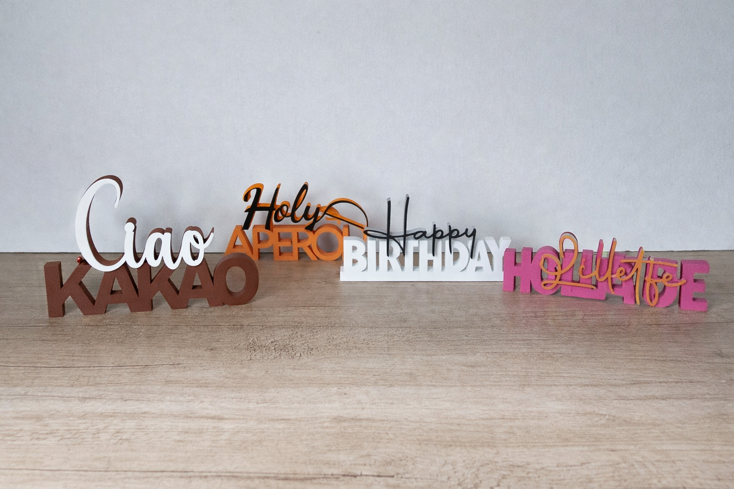 Colorful 3D-printed word signs by megahobby3dcreations on wood surface, creative decor.