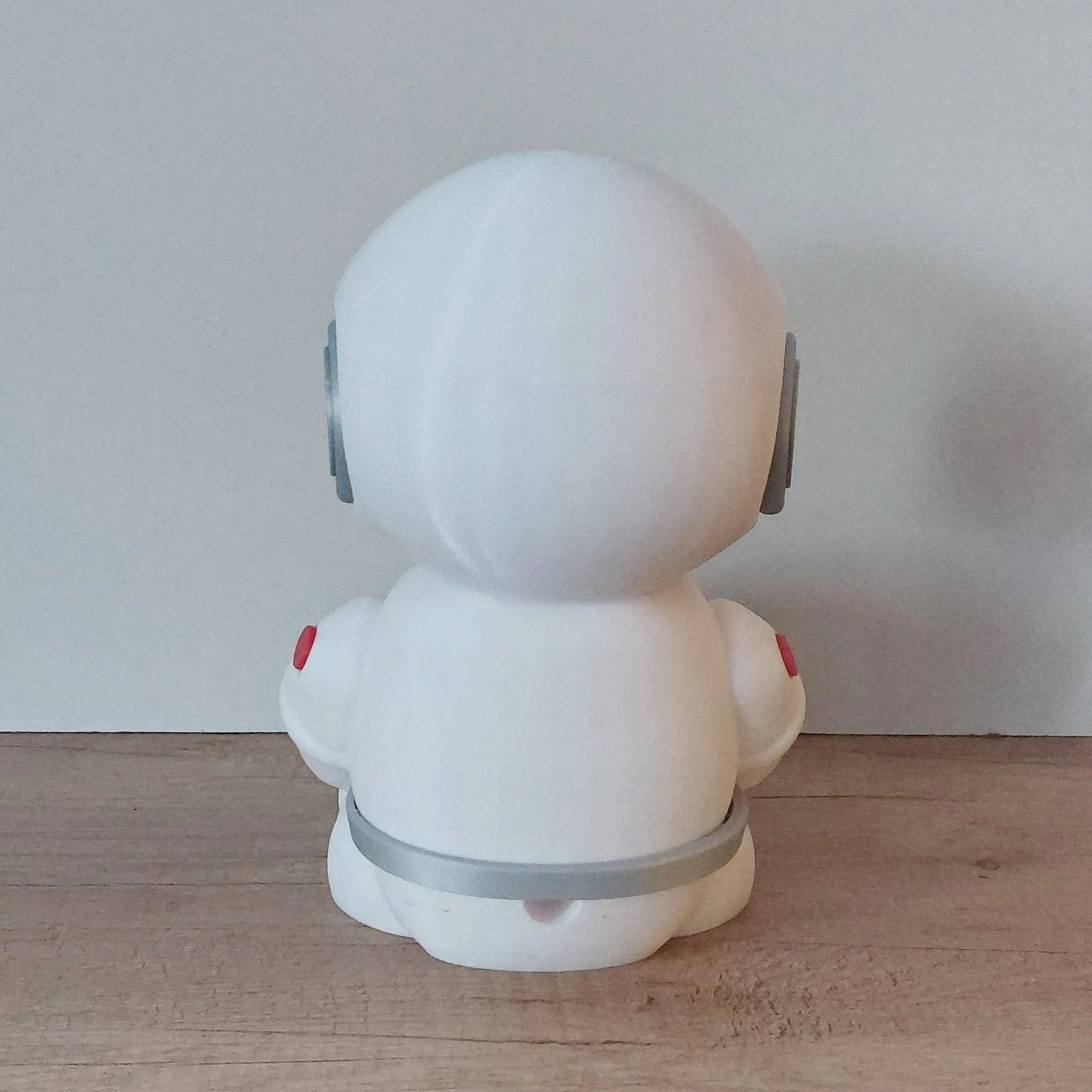 3D-printed white robot figure with gray and red details on wooden surface, megahobby3dcreations