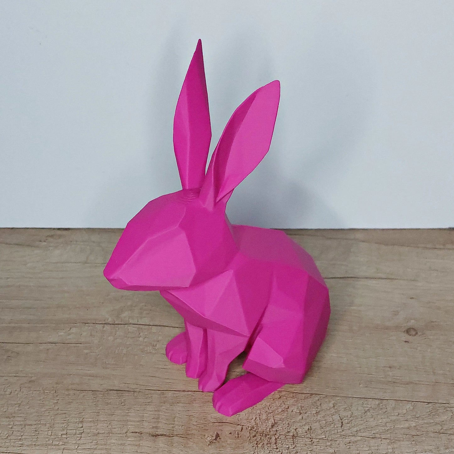 Pink low-poly 3D printed rabbit figurine by megahobby 3D creations on wooden surface