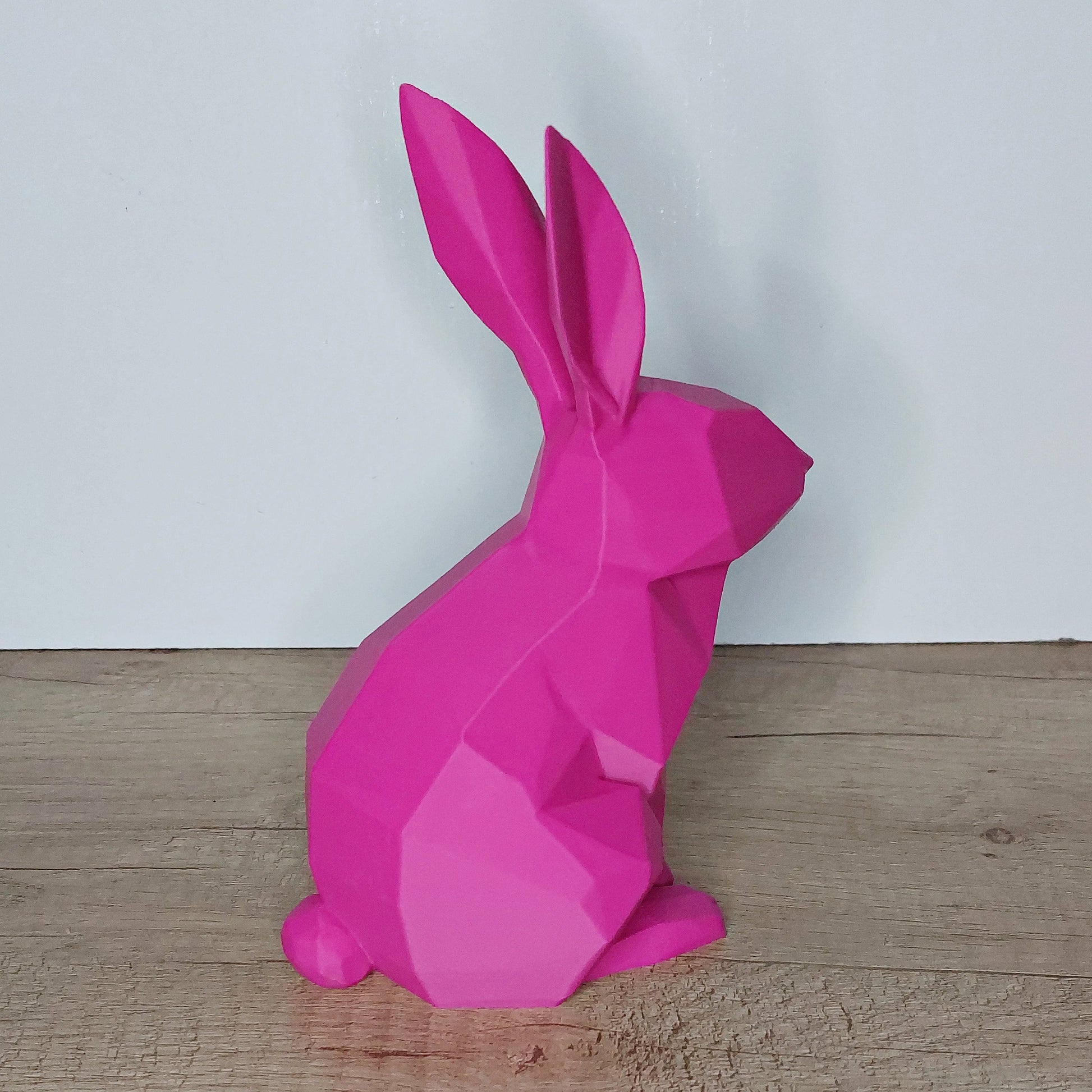 Pink low-poly 3D printed rabbit figurine from megahobby3dcreations on wood floor