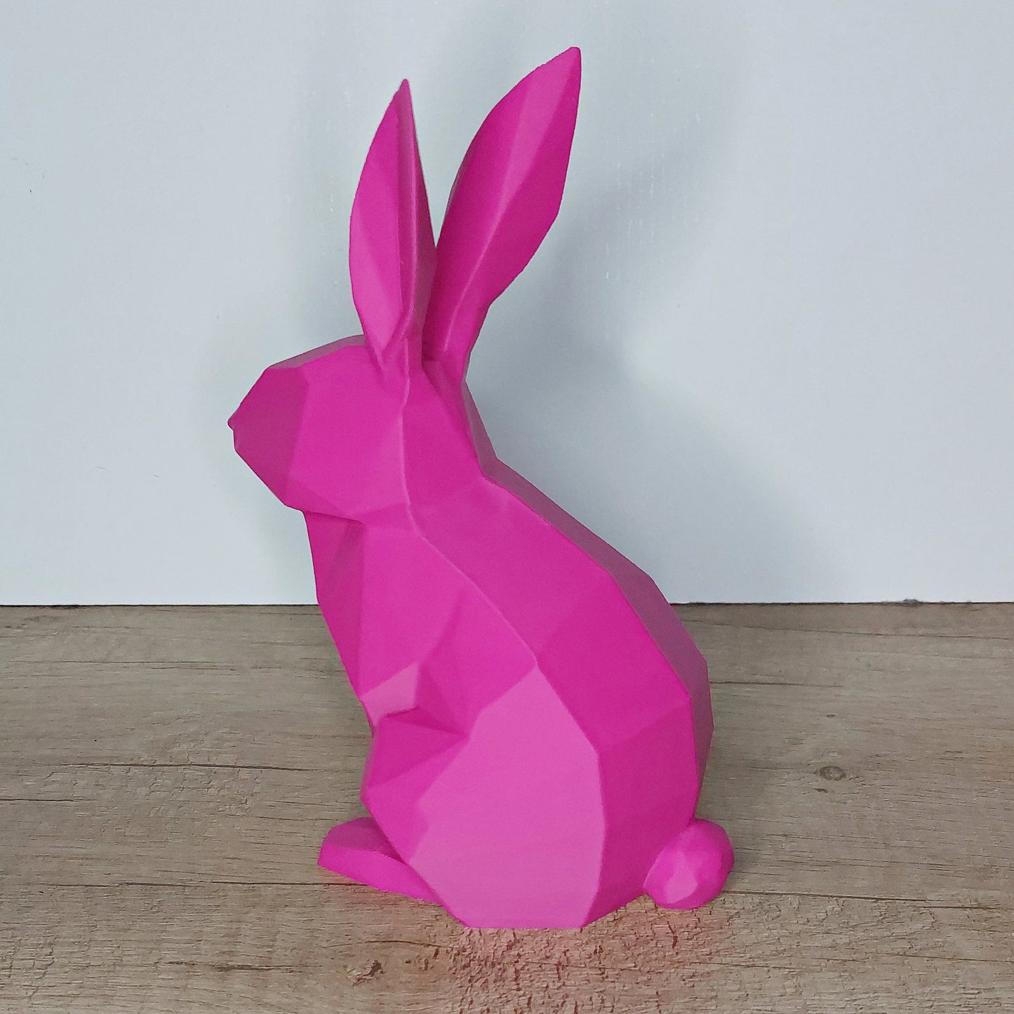 Pink low-poly 3D printed rabbit figurine on wooden surface by megahobby3dcreations