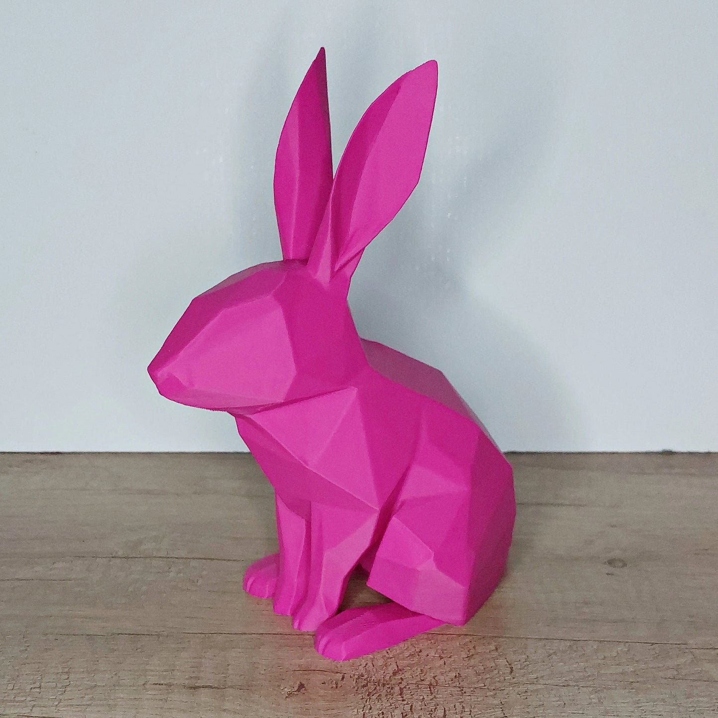 Pink geometric 3D printed rabbit figure on wooden surface by megahobby3dcreations