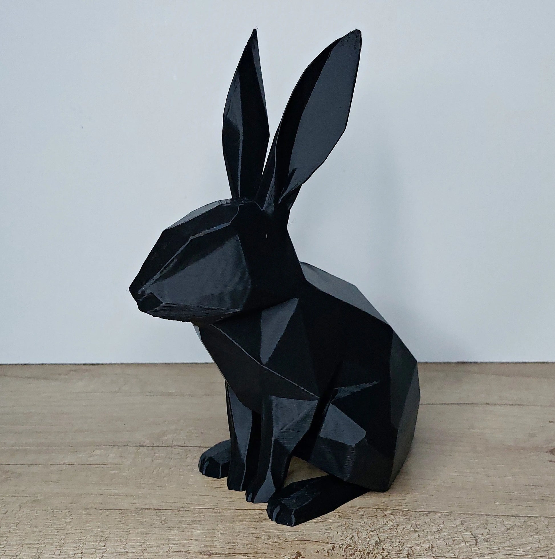 Black geometric 3D printed rabbit figurine on wooden surface by megahobby3dcreations
