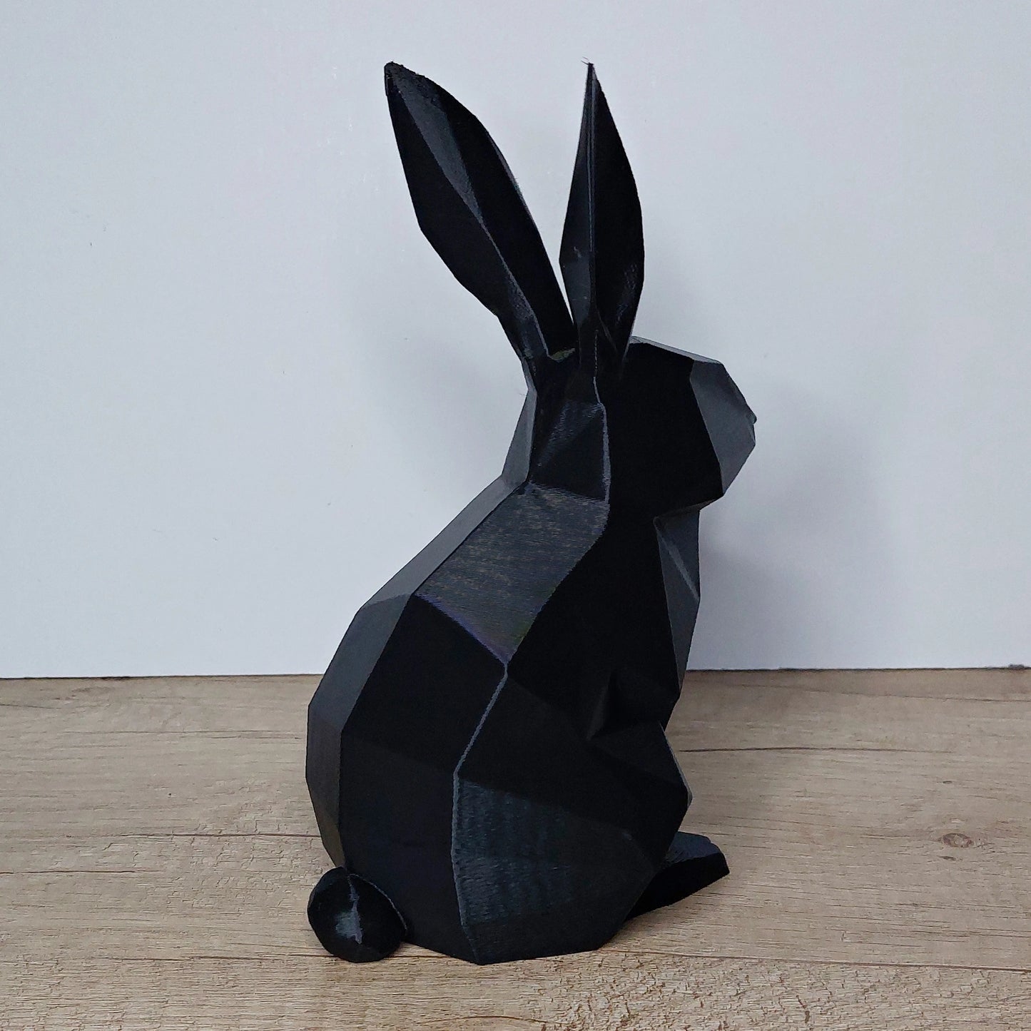 Black geometric 3D printed rabbit figurine by megahobby3dcreations on wood surface