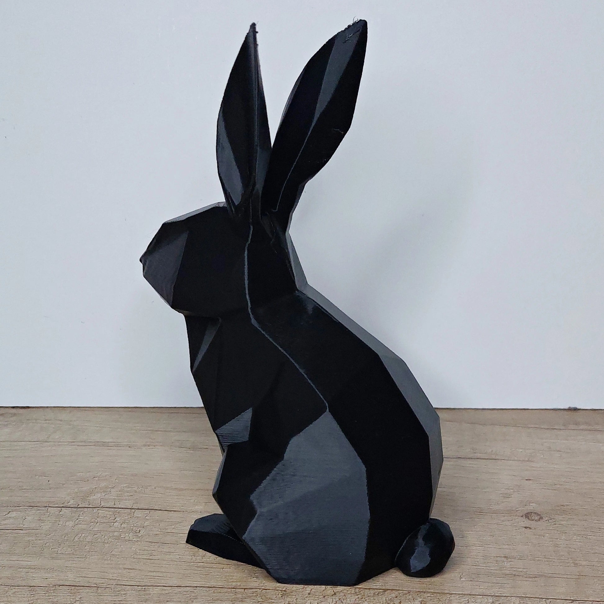 Black 3D printed geometric rabbit figurine by megahobby3dcreations on wood surface