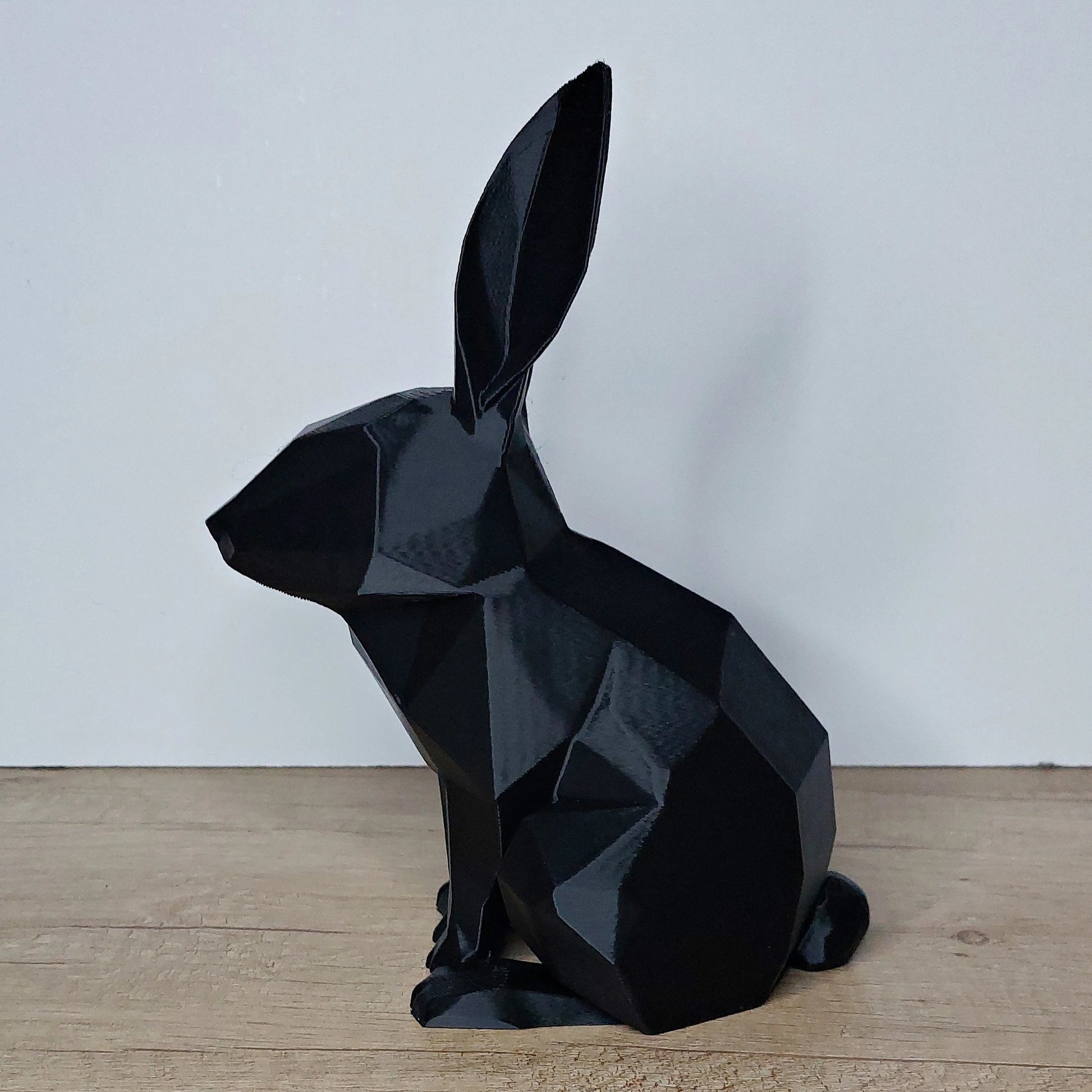 Black low-poly 3D printed rabbit figure on wooden surface by megahobby3dcreations