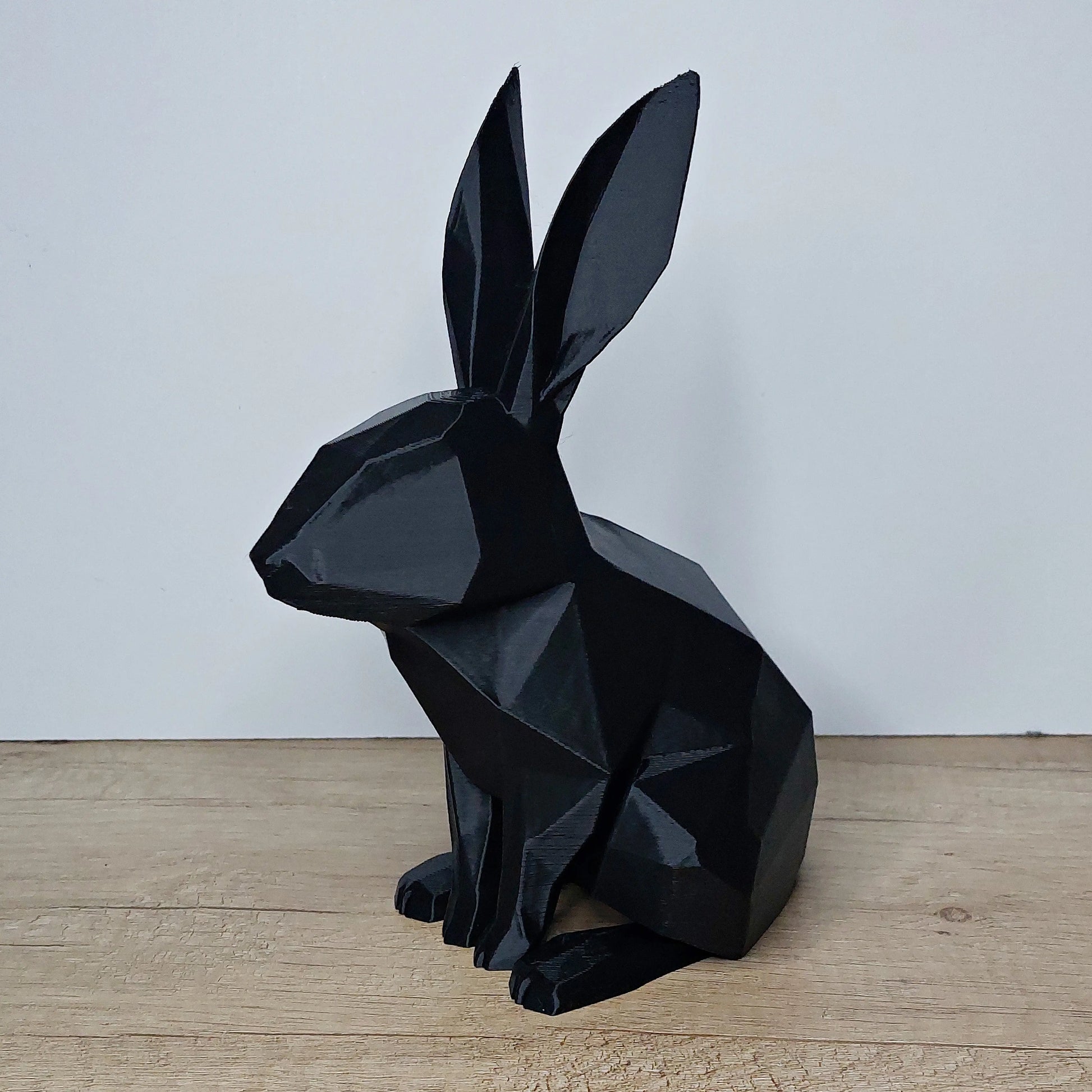 Black 3D printed geometric rabbit figurine on wooden surface by megahobby3dcreations